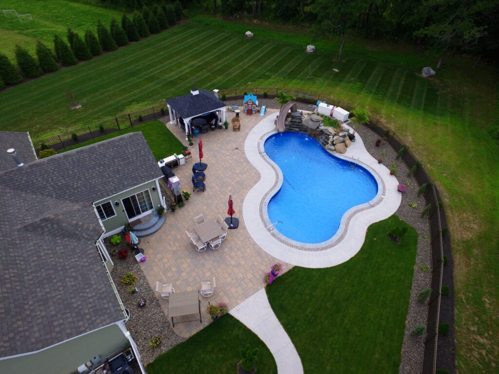 Aerial view of a freeform pool, paver patio and pavilion by Chaffee's