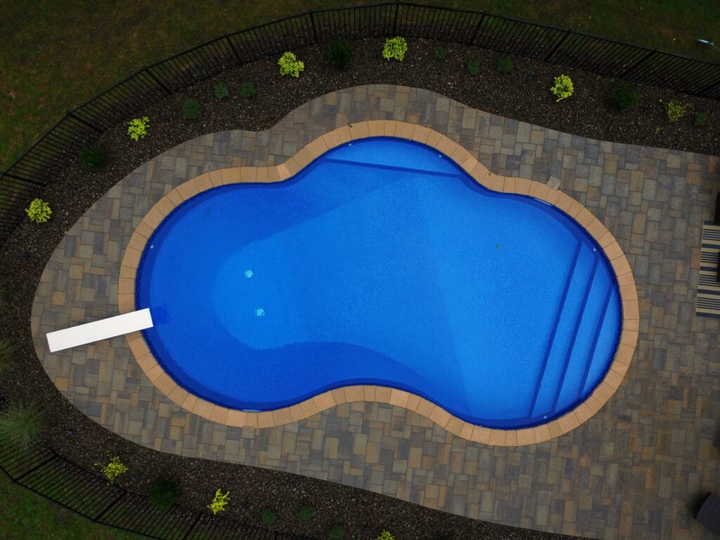 Overhead view of a kidney-shaped pool with paver deck and landscaping by Chaffee's