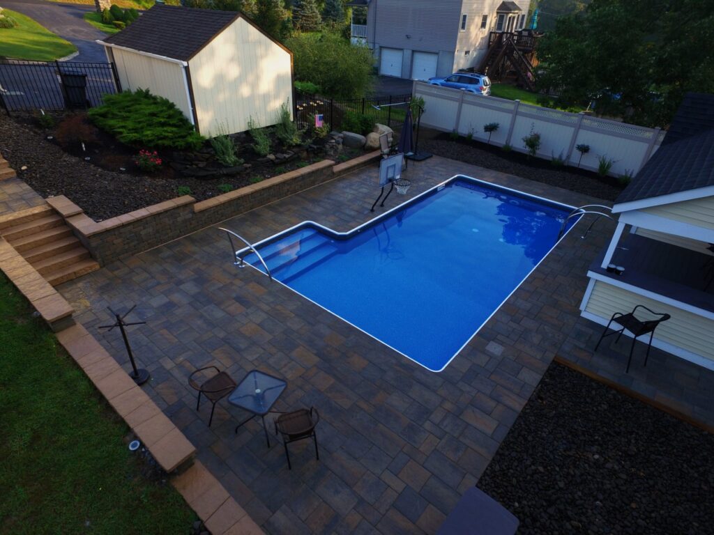 L-shaped pool with paver patio, steps and pool house by Chaffee's