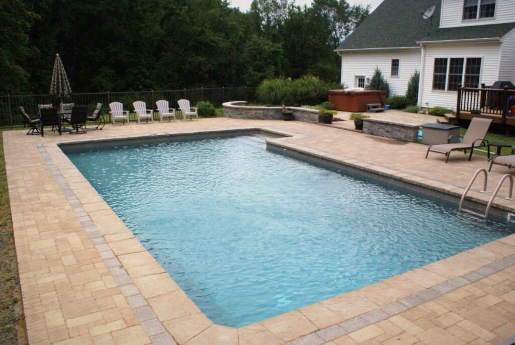 L-shaped inground pool with paver patio and seating wall by Chaffee's