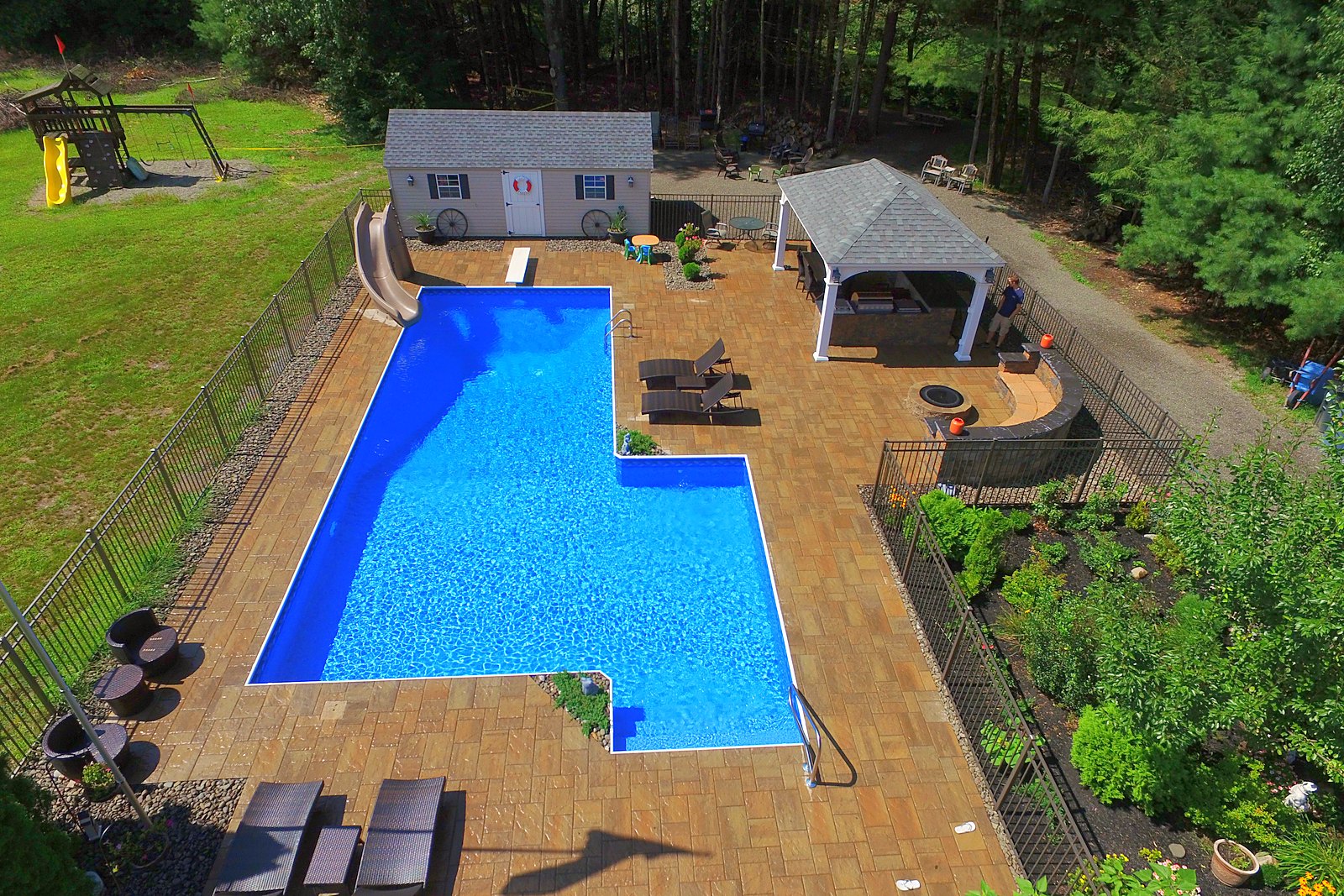 Finished L-shaped inground pool with slide, diving board, pavilion and fire pit built by Chaffee's
