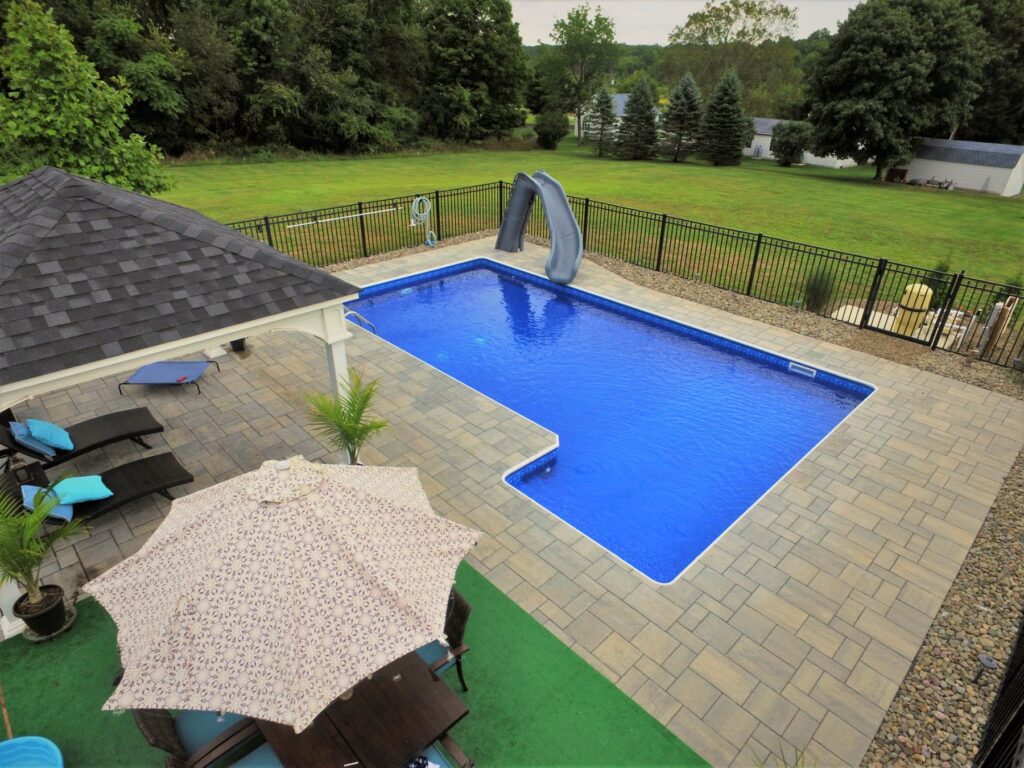 L-shaped inground pool with slide, pavilion and paver patio by Chaffee's