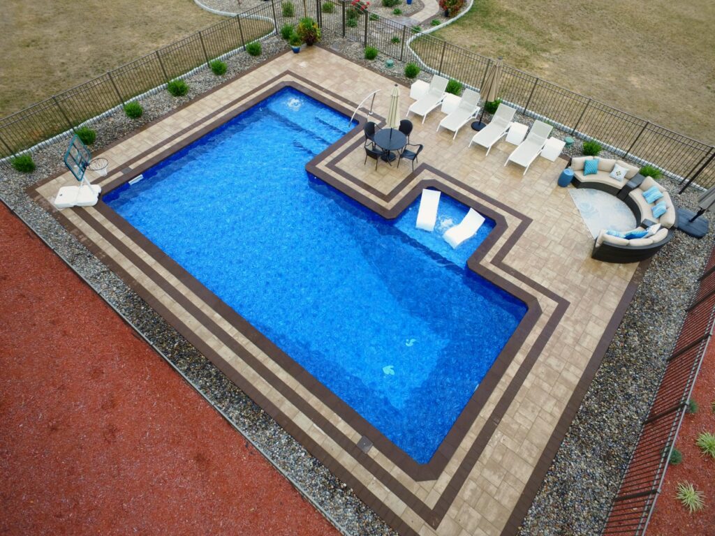 Custom L-shaped inground pool with sun shelf built by Chaffee's