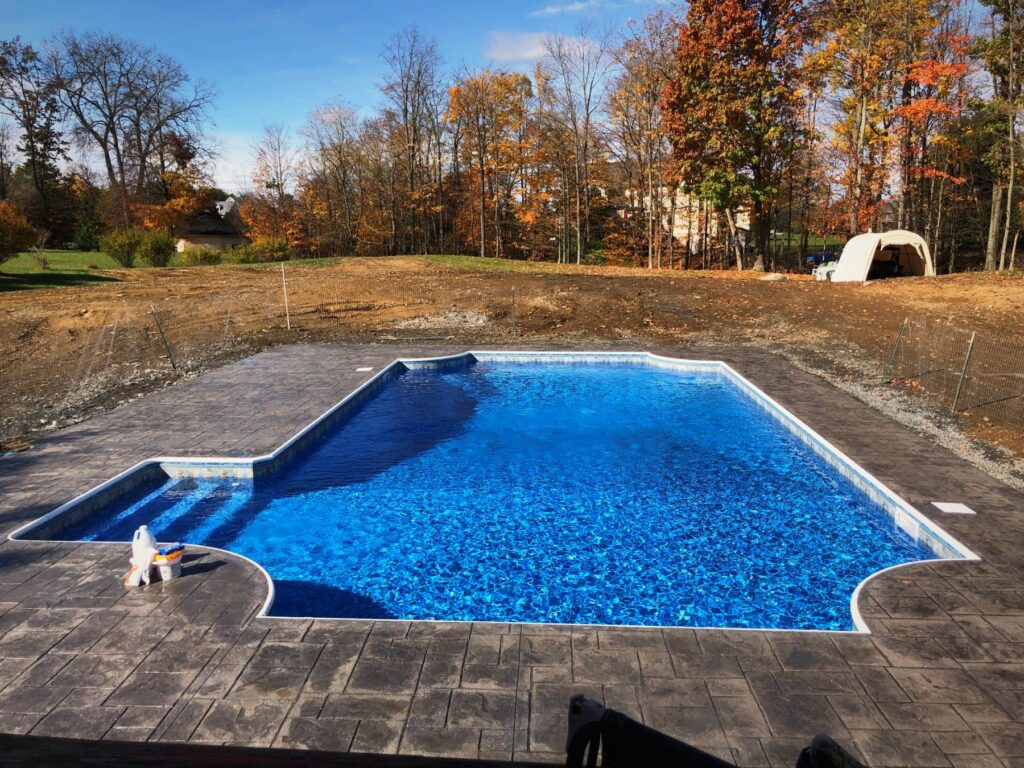 New inground pool with stamped concrete deck in autumn by Chaffee's