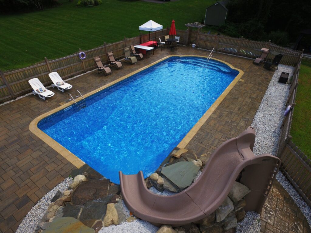 Inground pool with slide and natural stone surround by Chaffee's