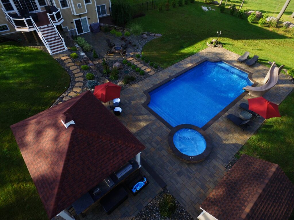 Pool with attached spa, pavilion and outdoor kitchen by Chaffee's