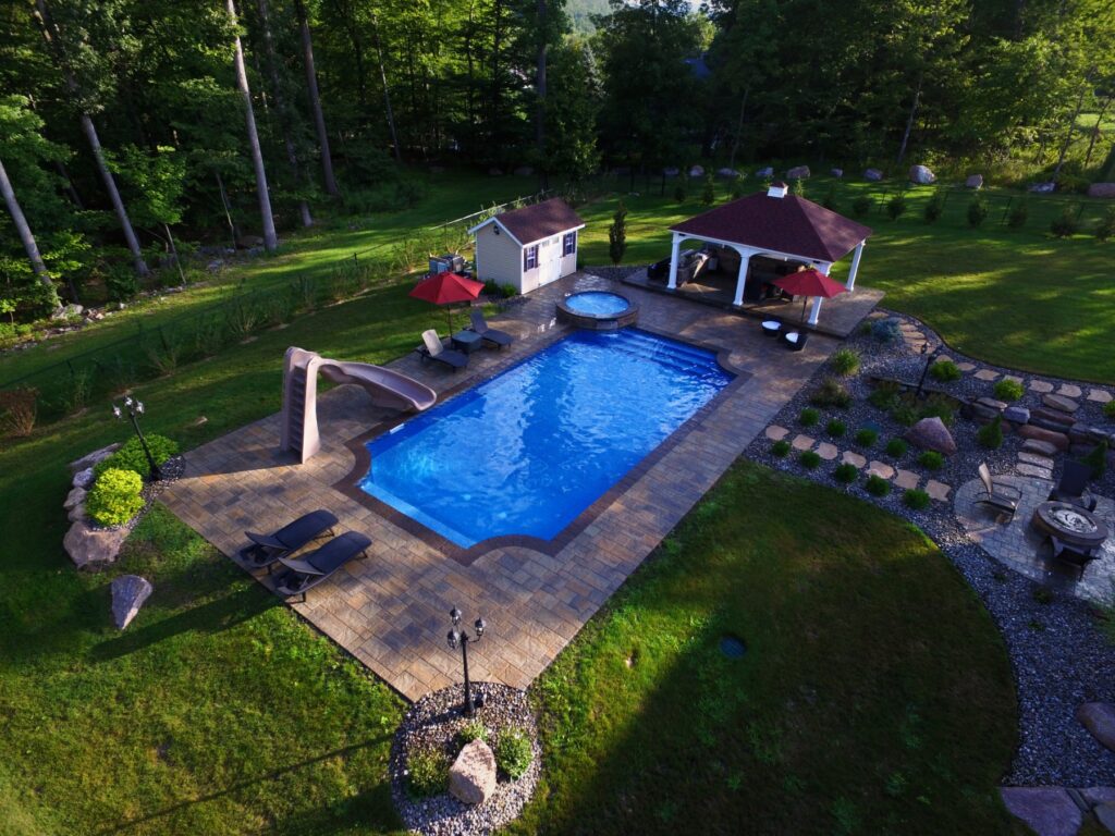 Inground pool with raised spa, slide, pavilion and fire pit by Chaffee's