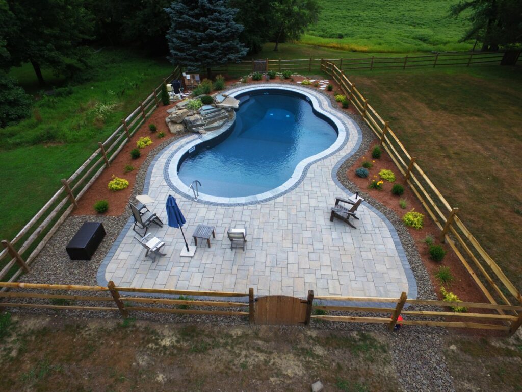 Inground pool with paver patio, landscaping and split-rail fence by Chaffee's