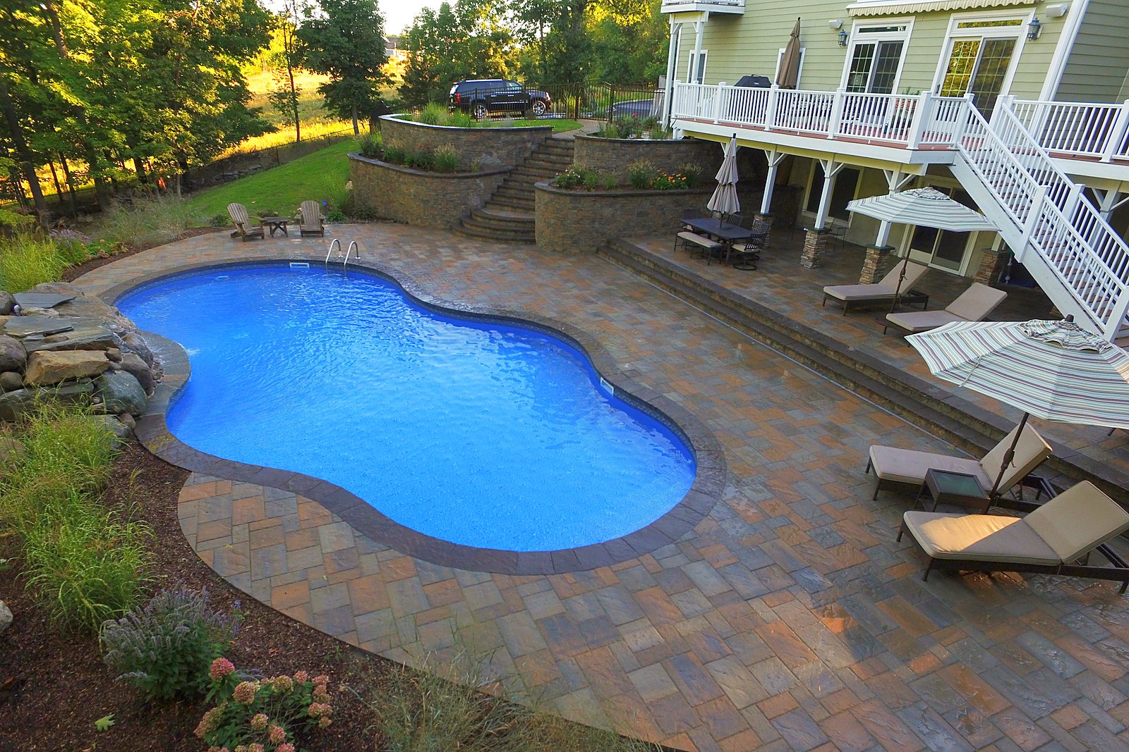 Finished freeform pool with rock waterfall, tiered retaining walls and paver patio built by Chaffee's