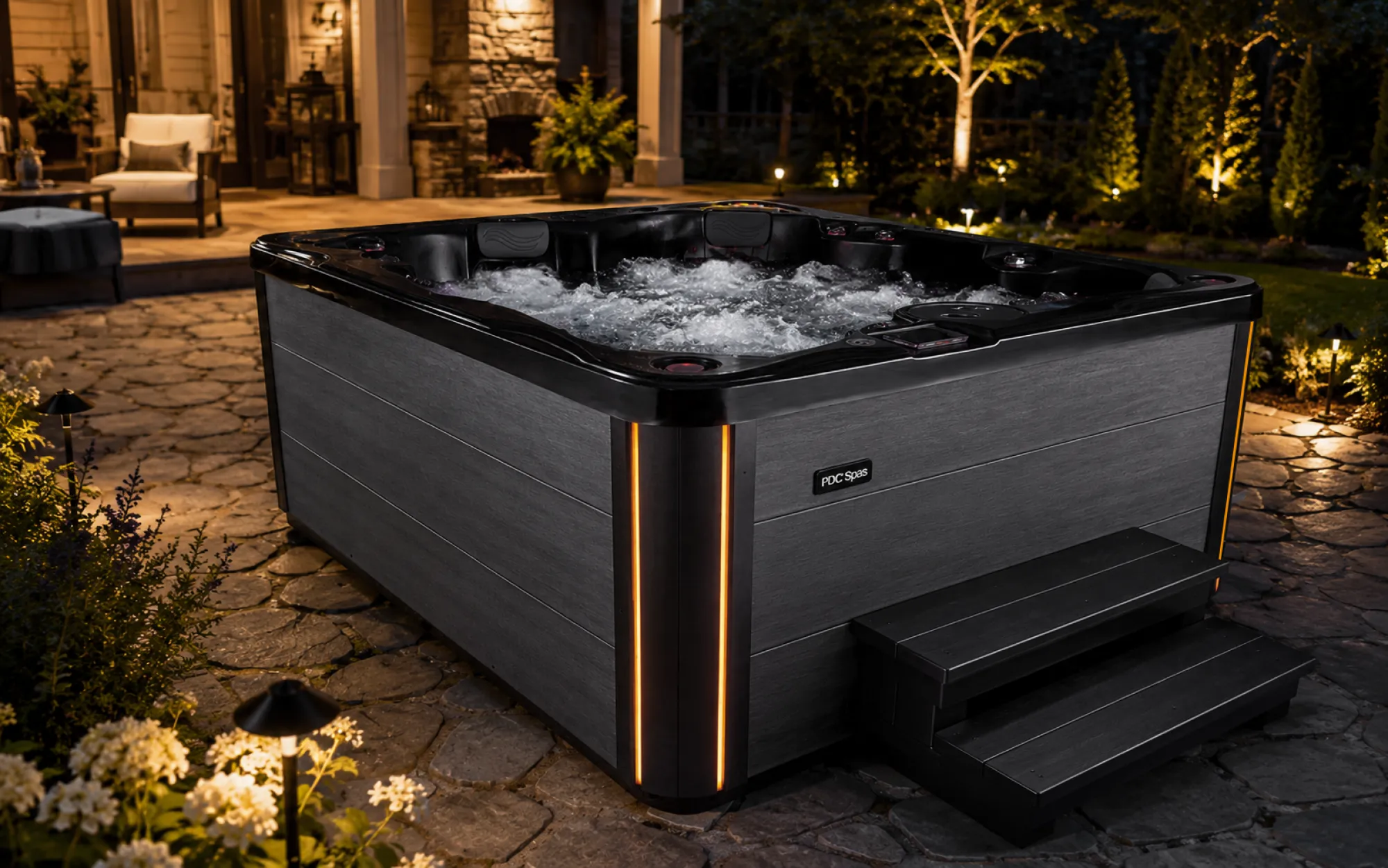 PDC Spas Midnight Series hot tub on a backyard patio at night